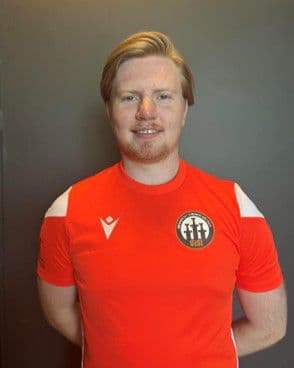 Portrett av en ung mann i rød fotballdrakt mot en grå bakgrunn.