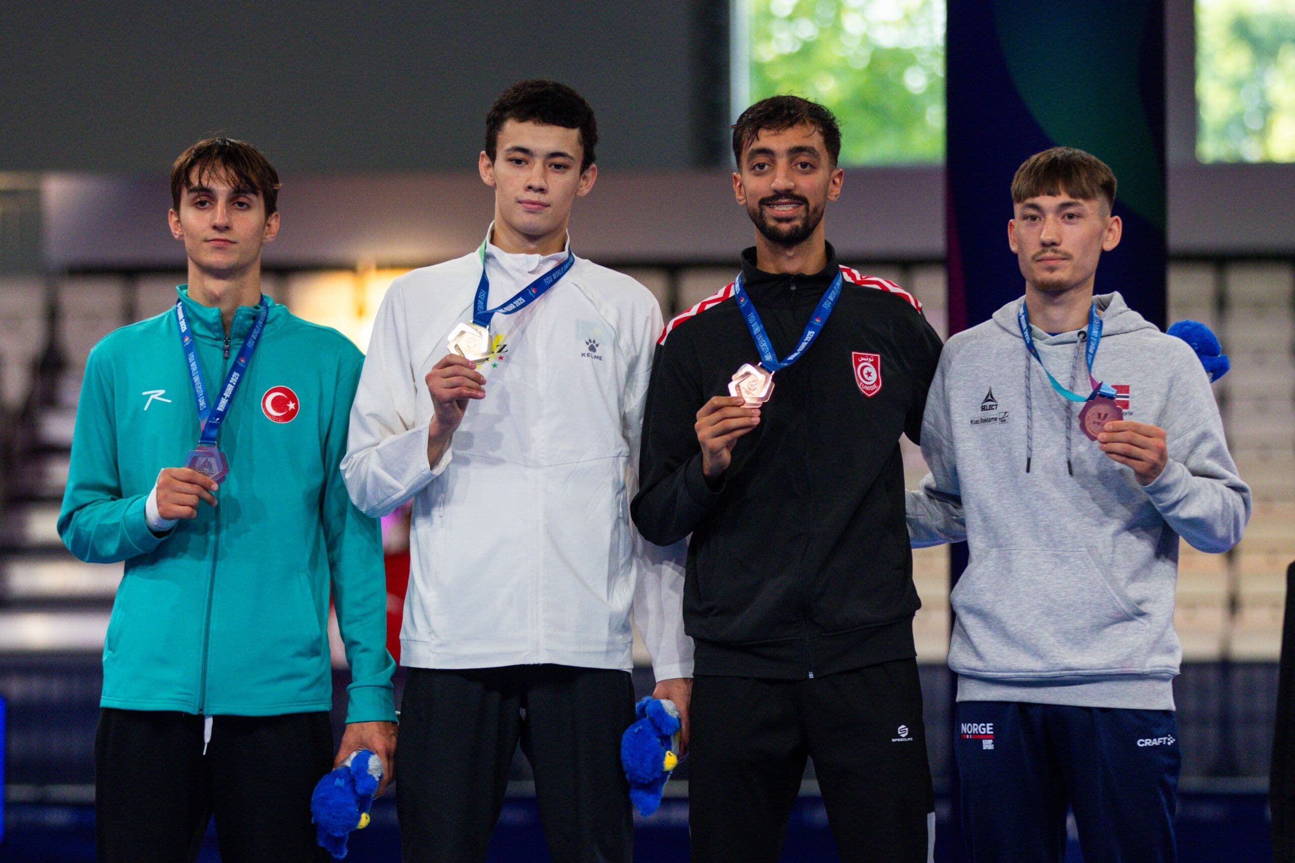 Fire mannlige taekwondoutøvere står på seierspallen og viser fram medaljene sine.