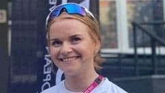 Portrett av en smilende kvinne med solbriller i håret utendørs.
