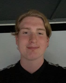 Portrett av en ung mann i svart genser innendørs.