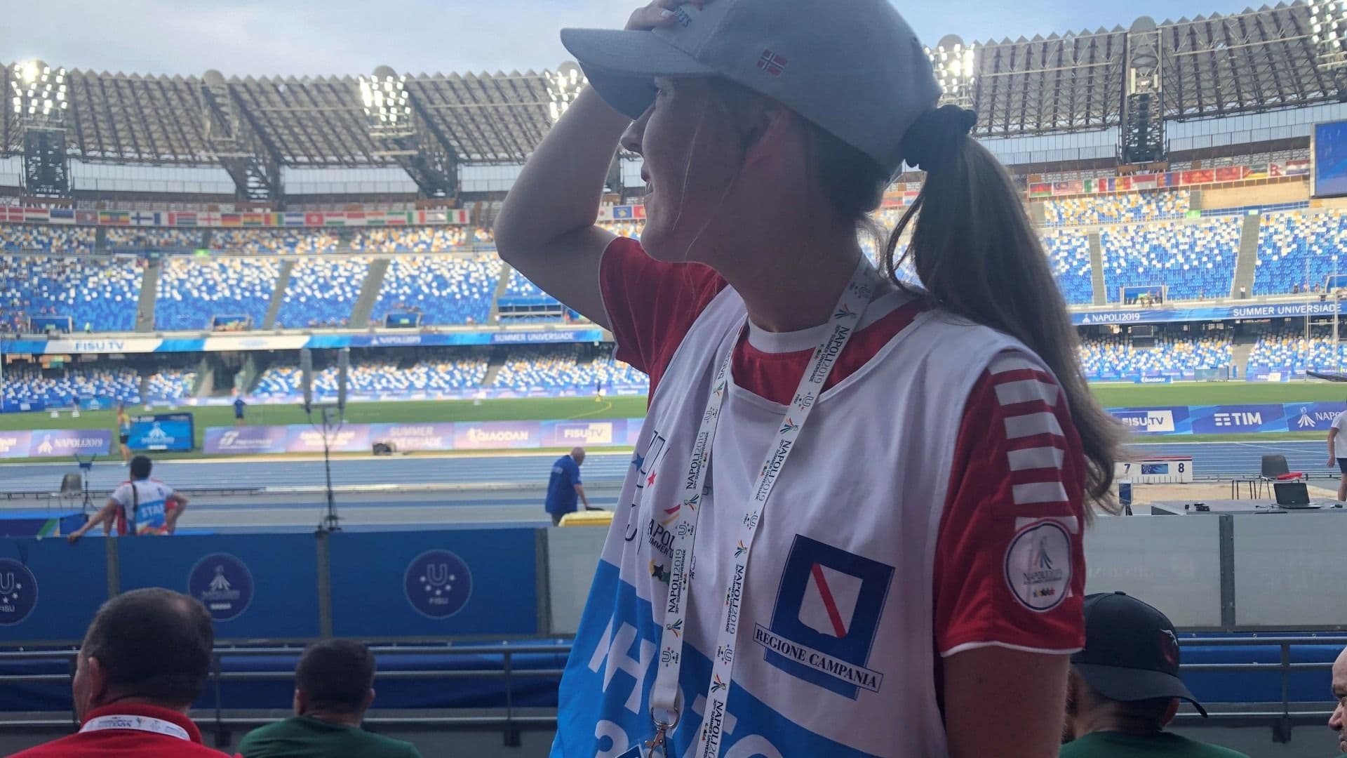 En kvinne skygger for øynene og ser utover et stort, nesten tomt stadion.