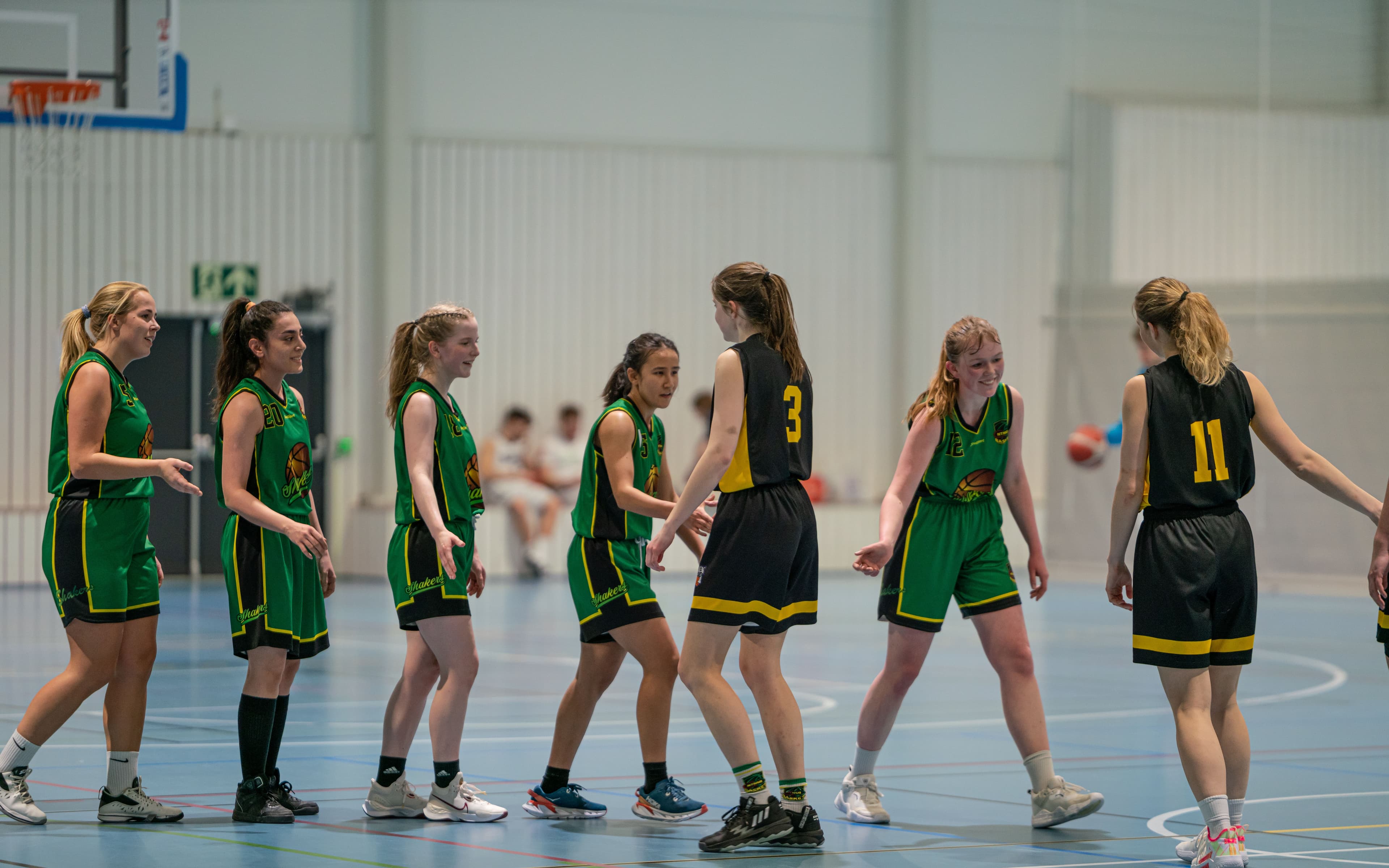 Kvinnelige basketballspillere i grønne og svarte drakter på banen under en kamp.
