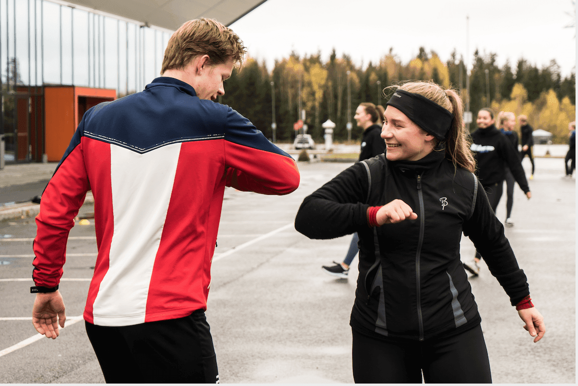 To studenter varmer opp utendørs og står klare til fysisk aktivitet.