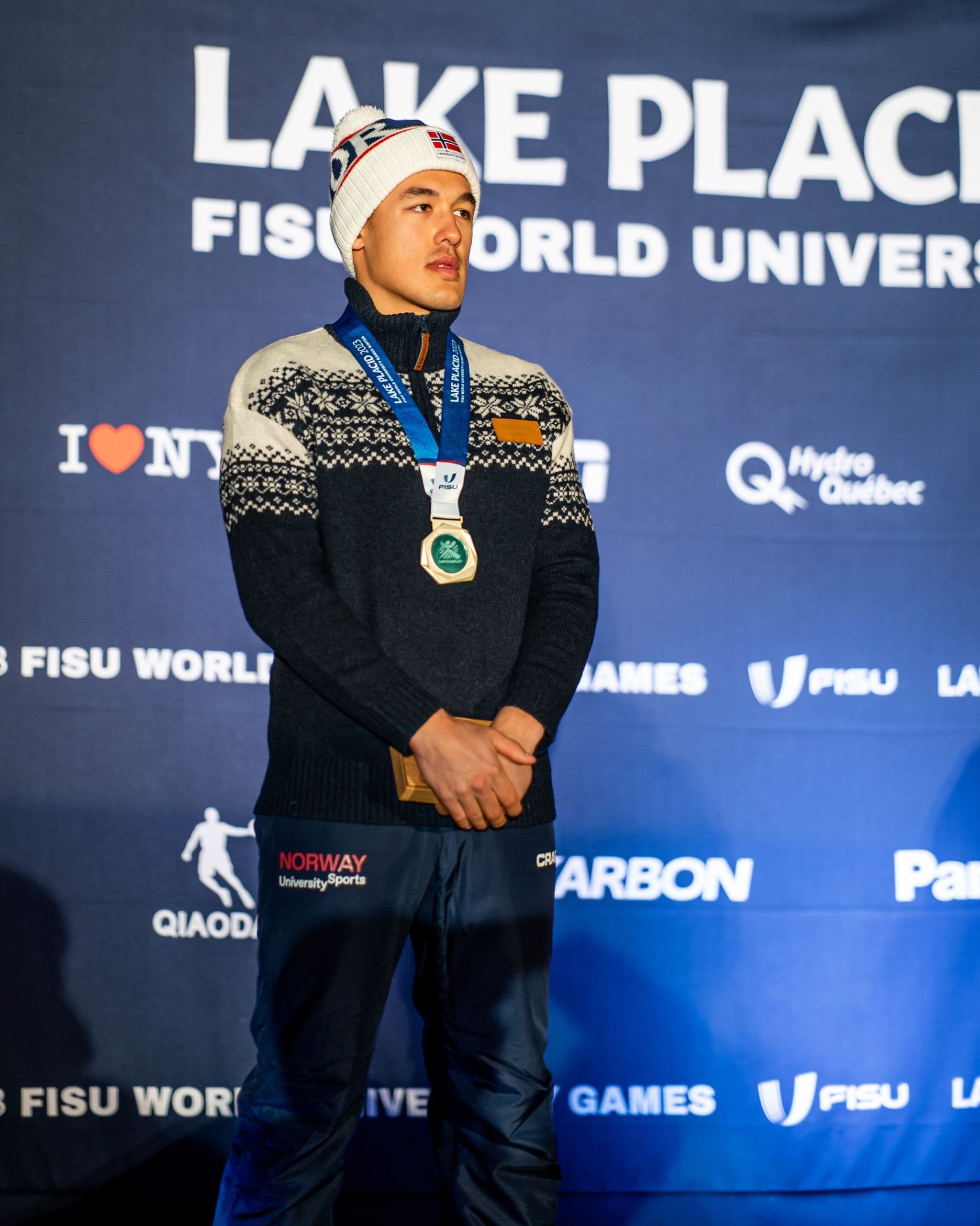 En utøver med medalje i en mønstret genser under premieutdelingen ved FISU World University Games i Lake Placid.