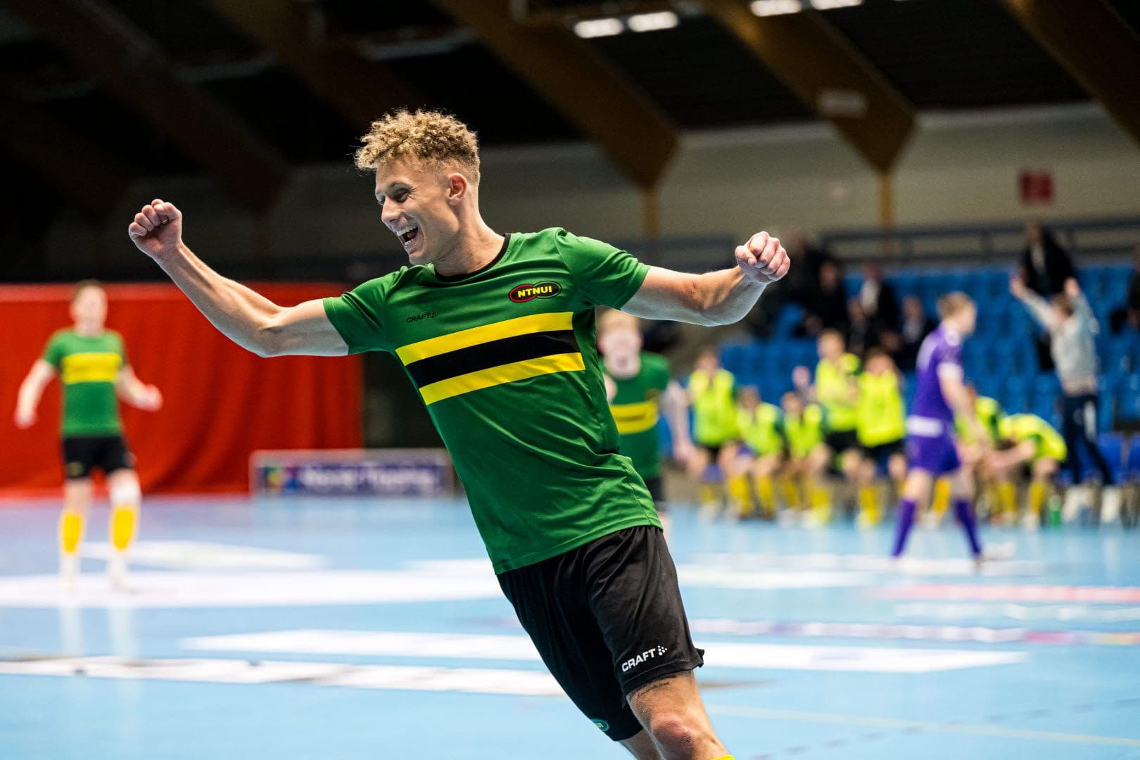 En futsalspiller i grønn NTNUI-drakt jubler i idrettshallen.