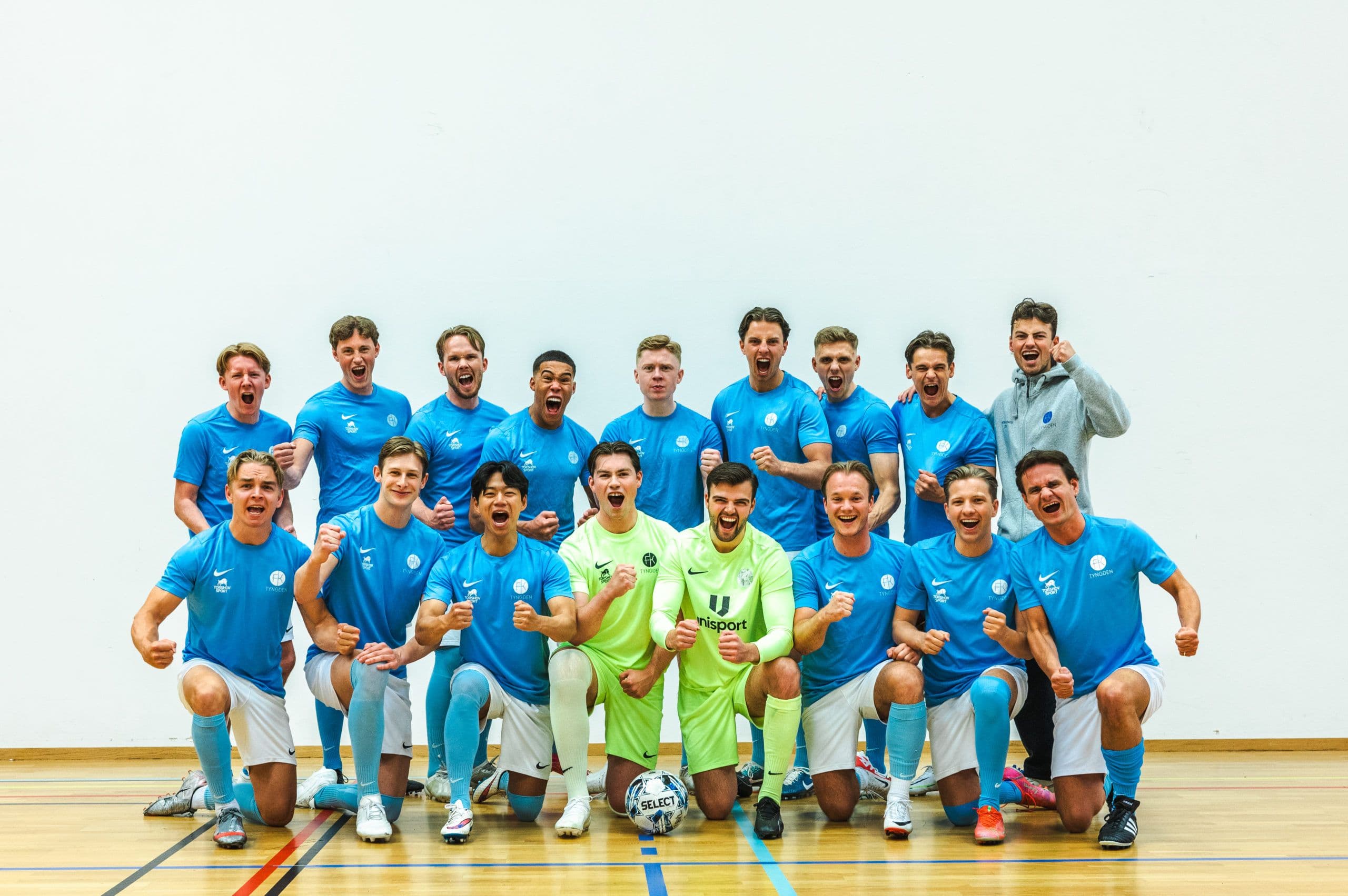 Et futsallag i lyseblå drakter poserer samlet i en idrettshall.