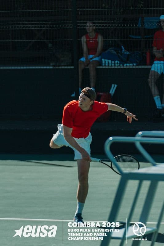En tennisspiller i rød trøye følger igjennom en serve under Coimbra 2025-mesterskapet.