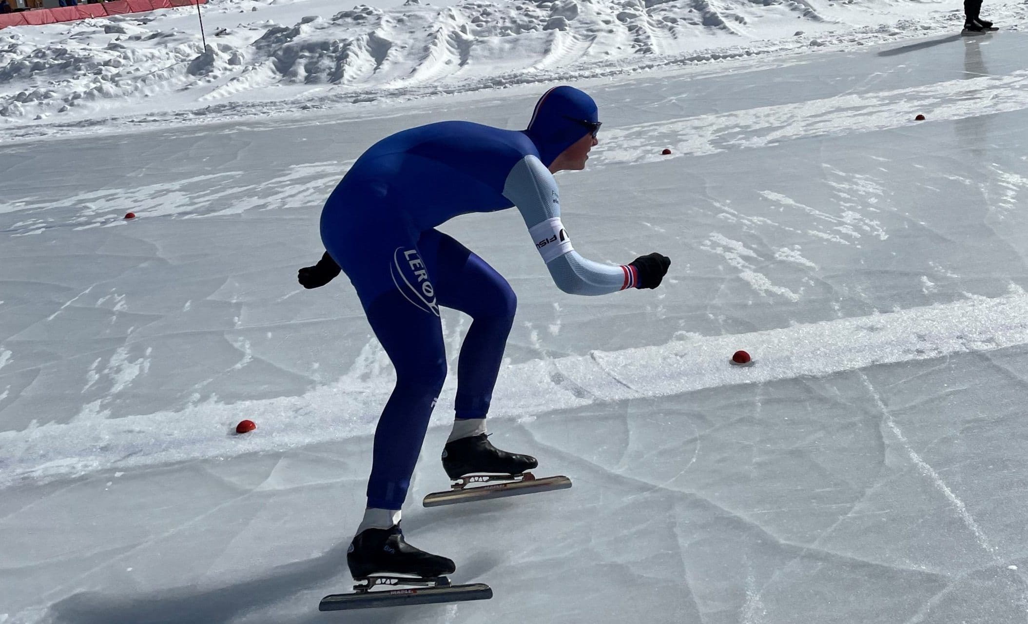 En skøyteløper i blå drakt i fart på isbanen under en skøytekonkurranse.
