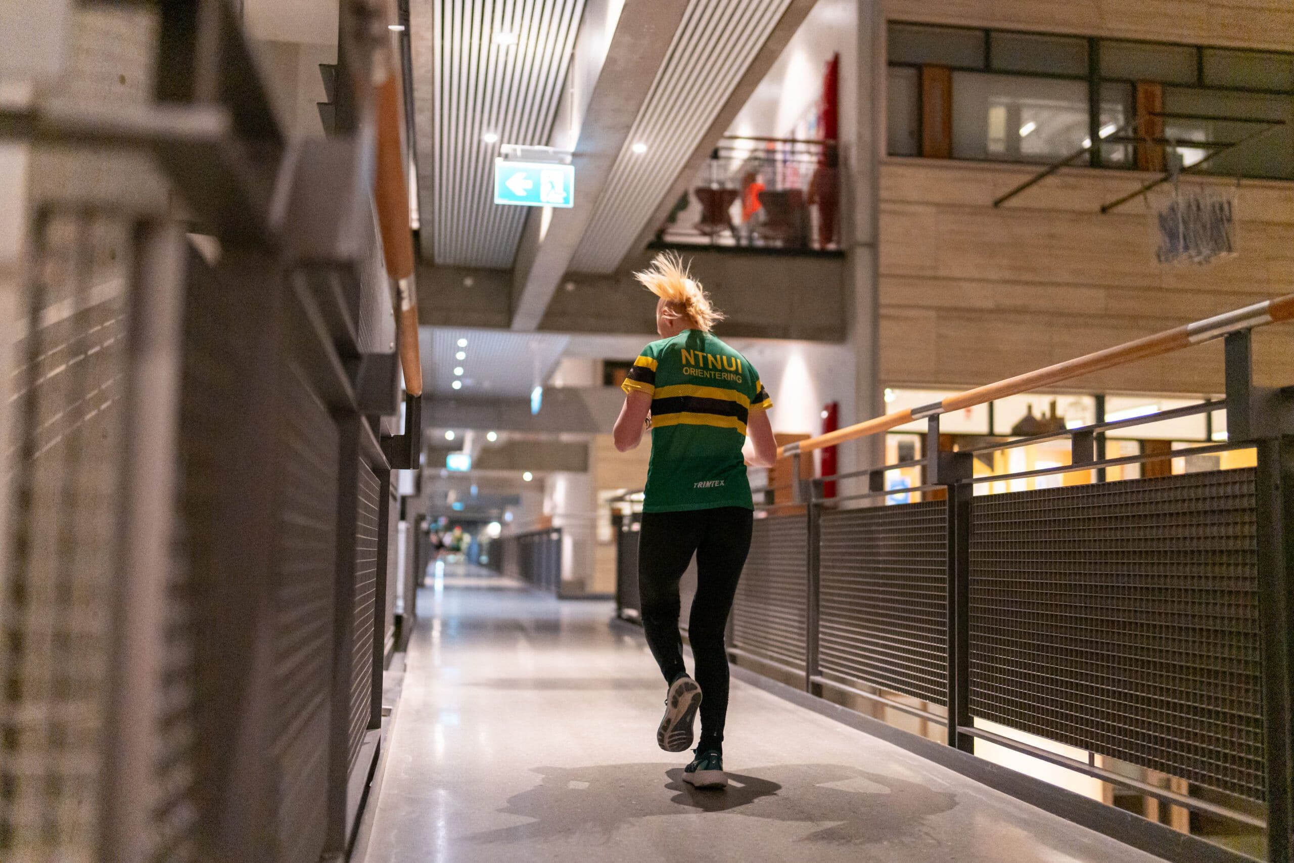 En kvinne løper gjennom en korridor i et campusbygg om kvelden.