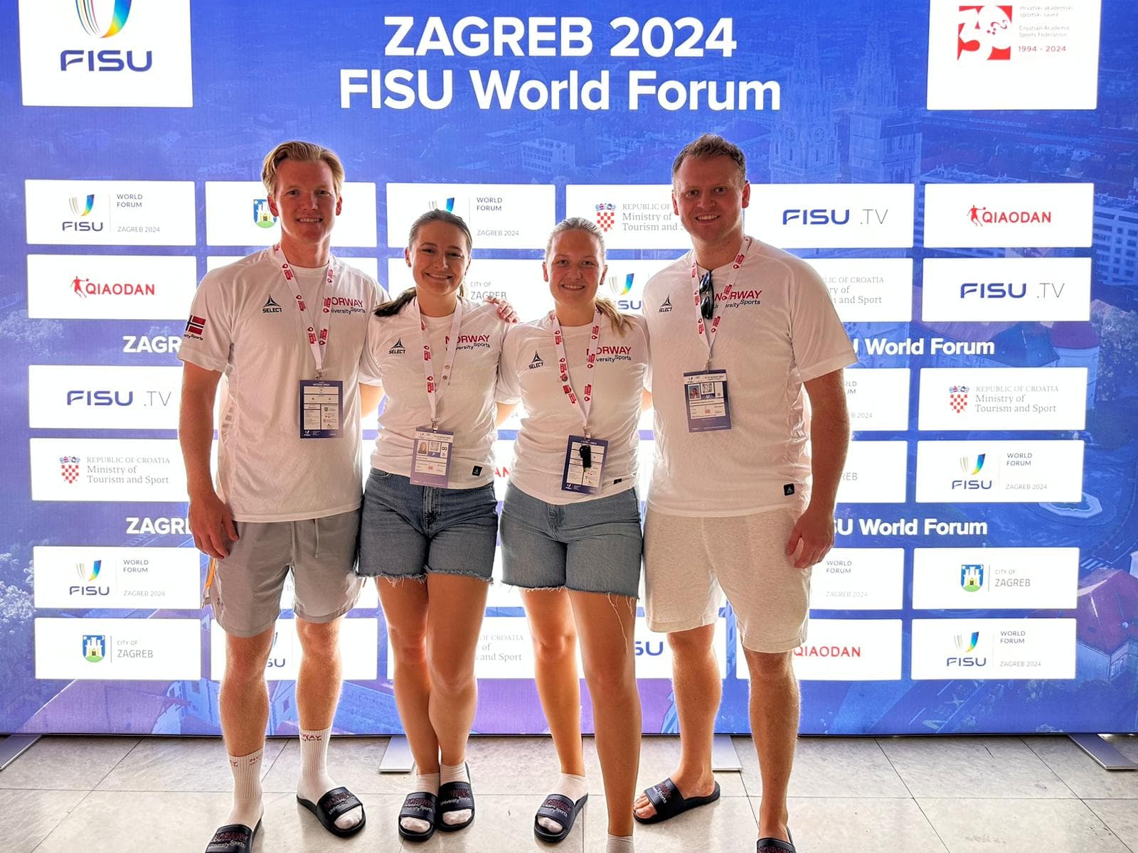 Fire personer poserer foran en vegg med teksten Zagreb 2024 FISU World Forum.