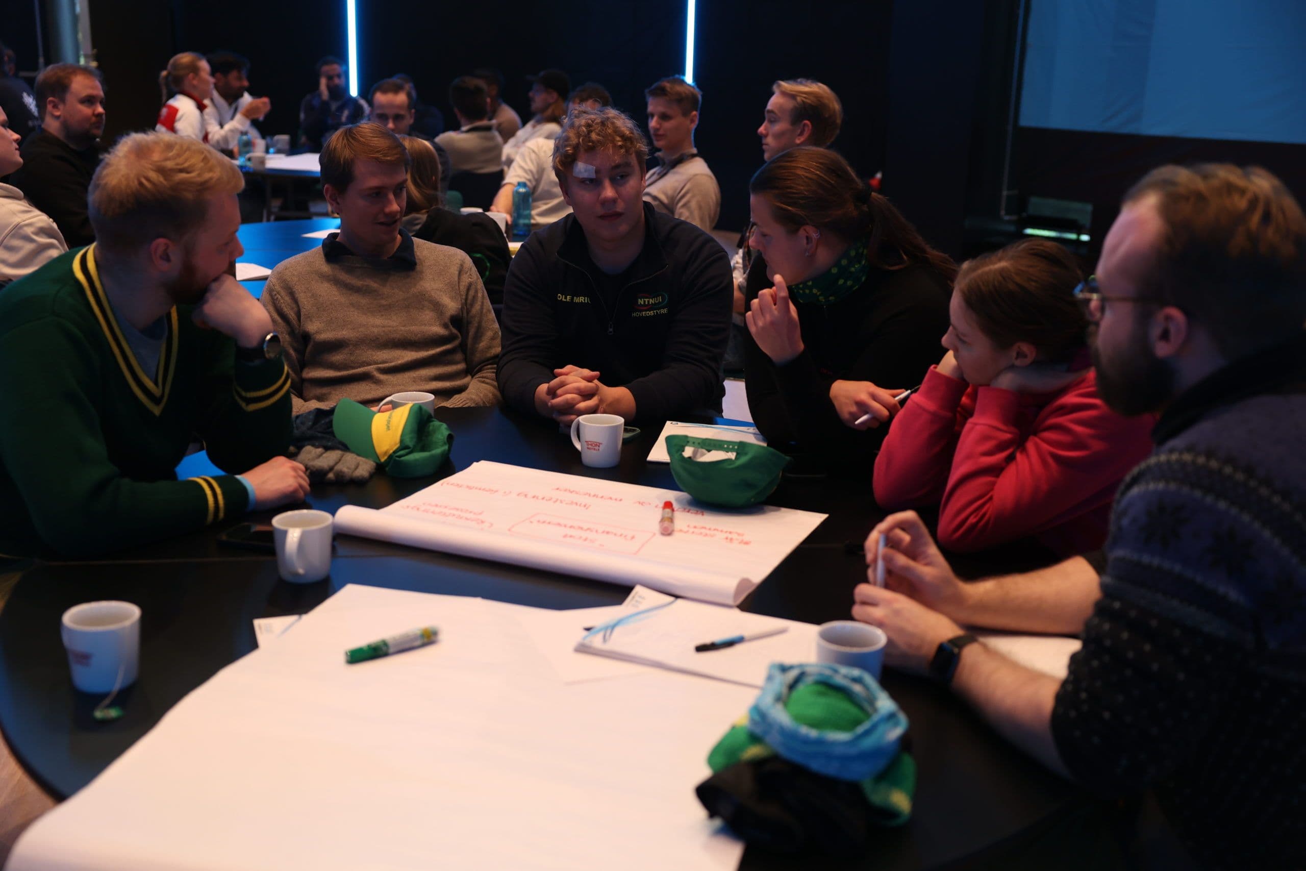 En gruppe deltakere jobber sammen rundt et bord med flippover under et seminar.