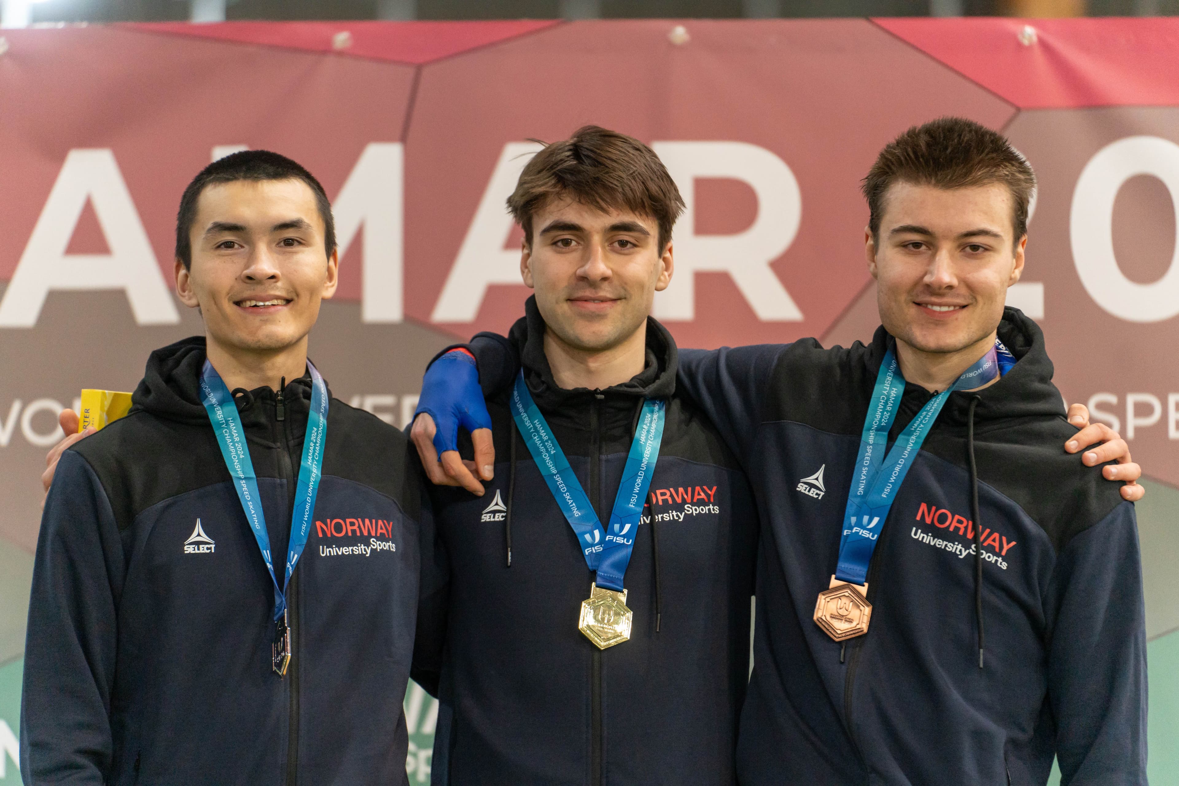 Tre mannlige utøvere med medaljer og jakker fra Norway University Sports poserer sammen.