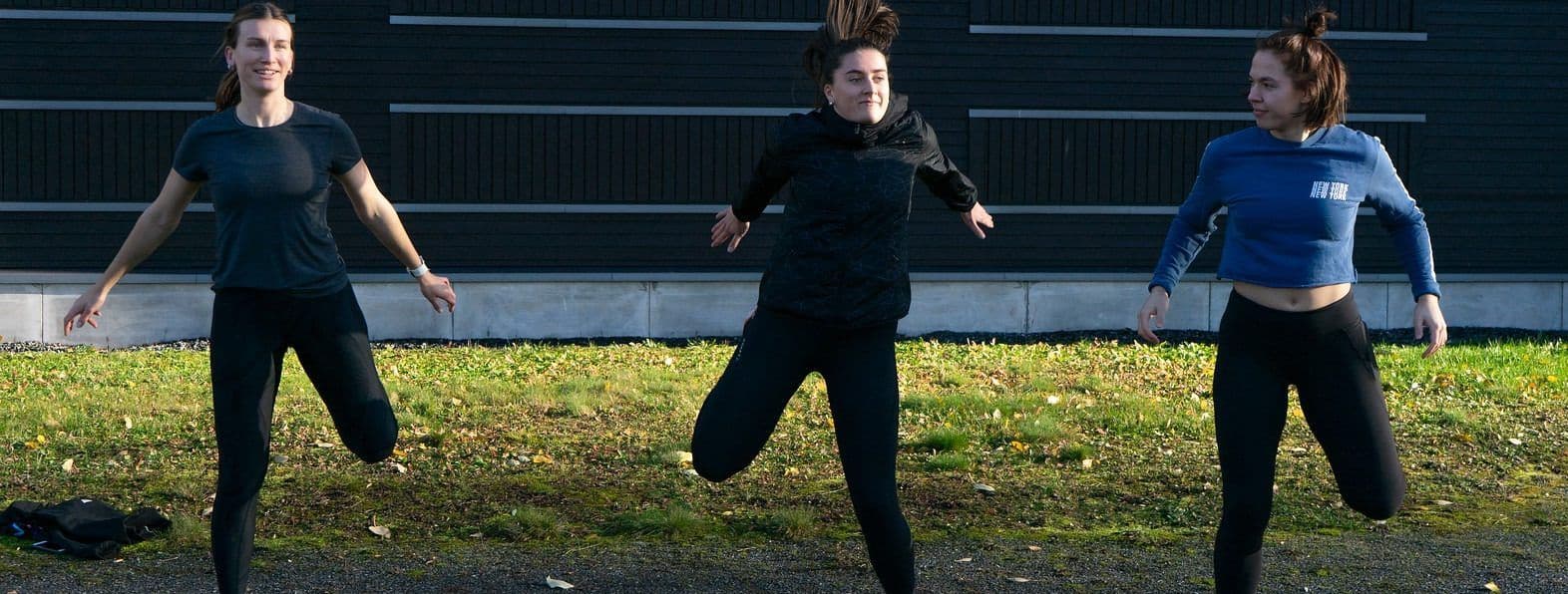 Tre kvinner trener og hopper med spretthopp på en utendørs bane.